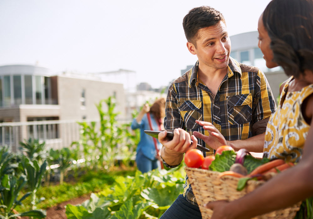 Friendly San Jose craft food farmers market vendor selling vegetables to a customer.