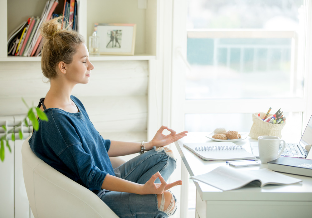 Woman taking a break to meditate in her home office