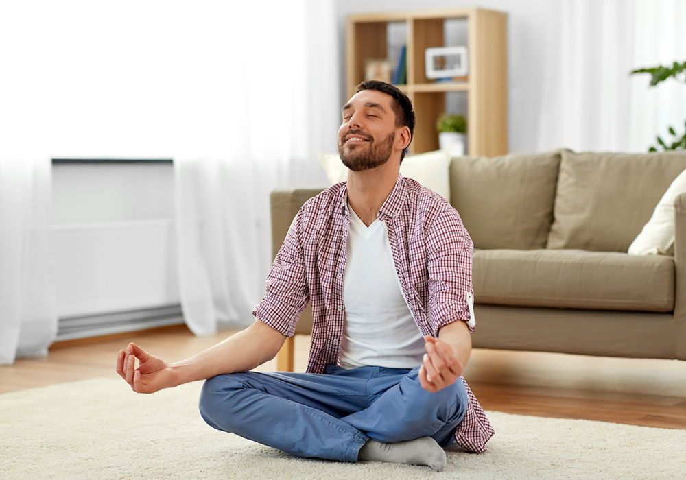 Man develops a meditation practice in the middle of his apartment living room.