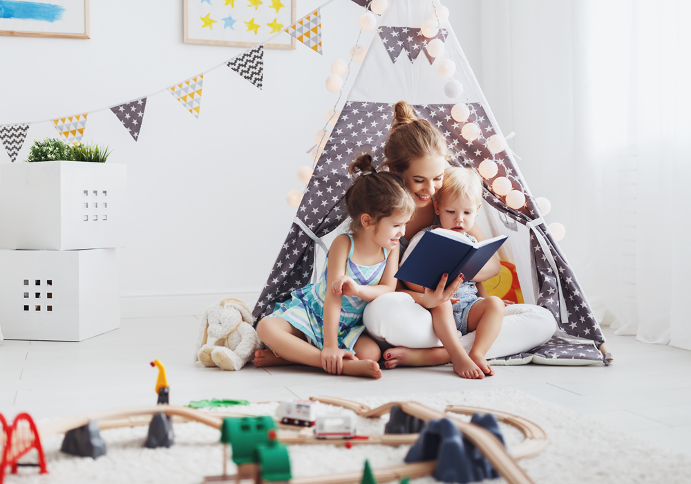 Mother reading to her two kids while sitting in a small indoor tent.