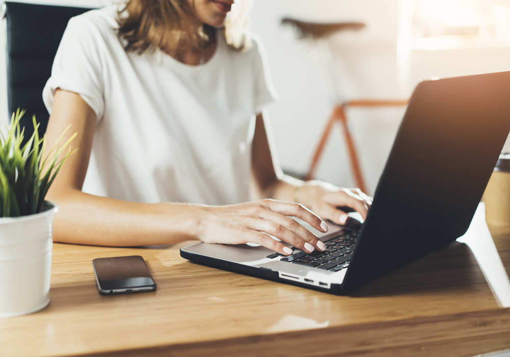Woman typing on laptop at her home office desk.