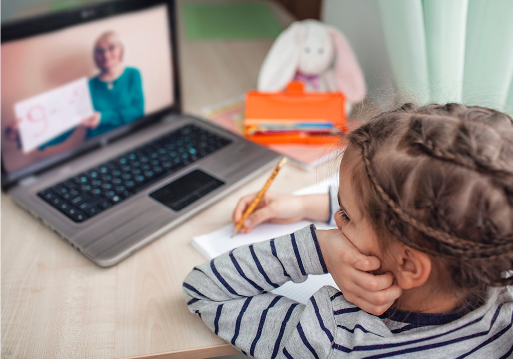 Kid using laptop to learn online from his apartment home