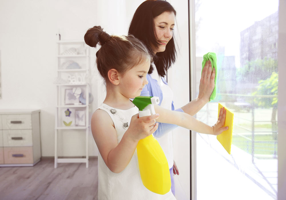 Mother and daughter spring cleaning their apartment window.