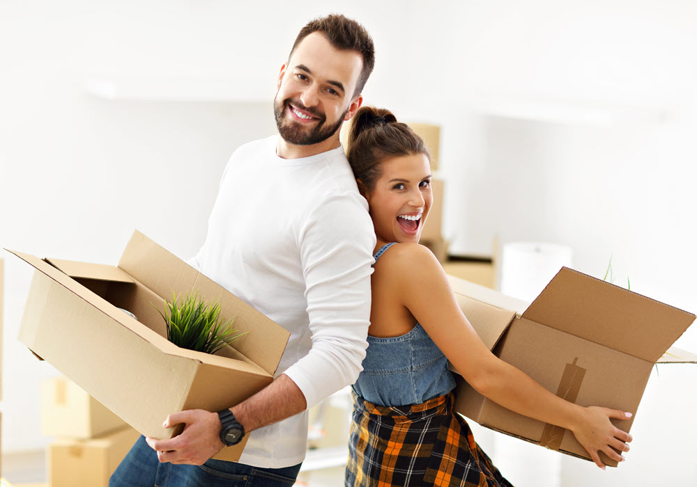 Couple holding moving boxes.