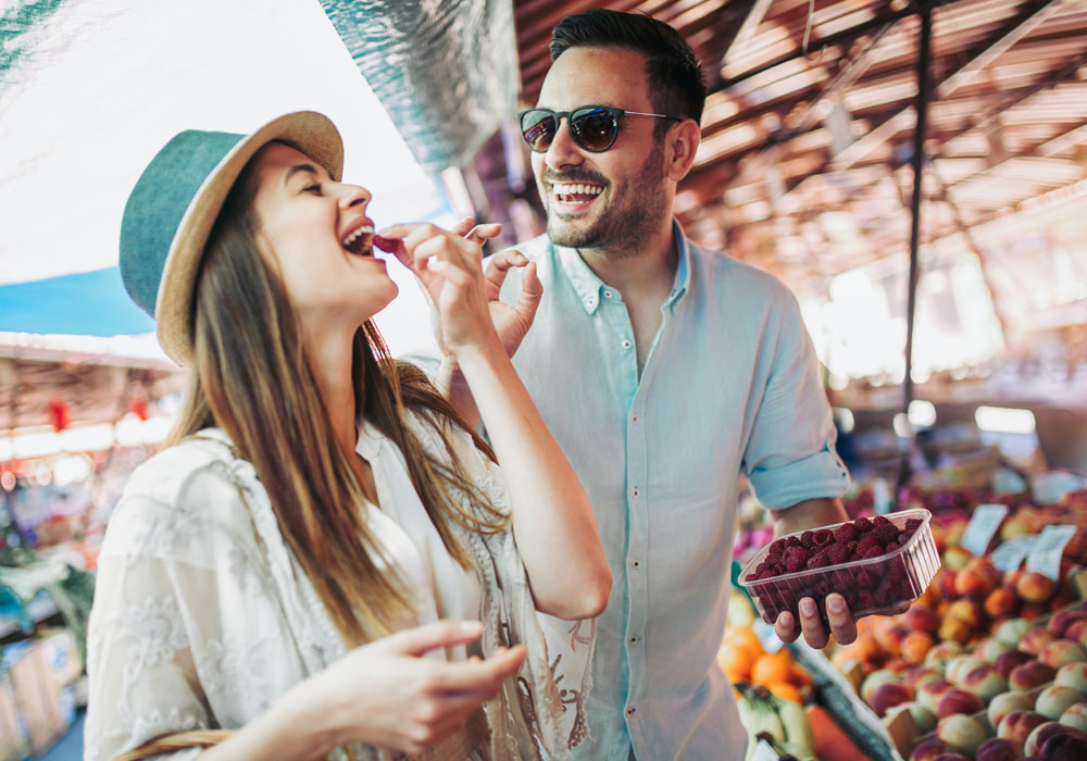 Couple at Farmers Market sampling fruit