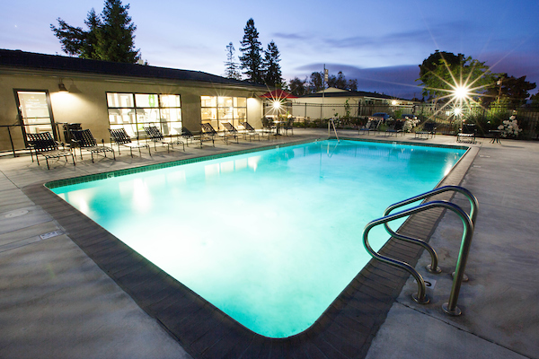 Outdoor swimming pool area surrounded by lounge chairs at dusk.