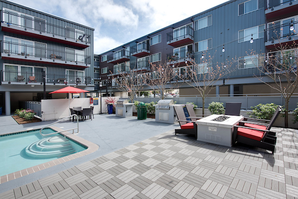 Outdoor swimming pool surrounded by lounge seating, outdoor fireplace, and BBQ area.