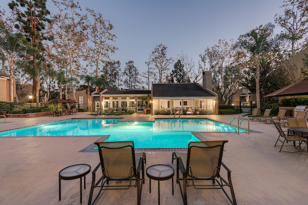 Outdoor swimming pool area with lounge seating at dusk.
