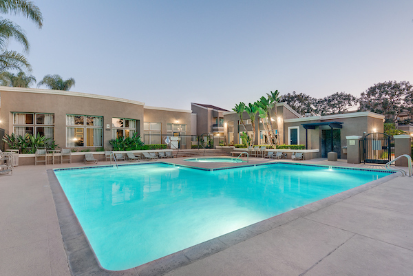 Outdoor spa and swimming pool surrounded by lounge chairs at dusk.